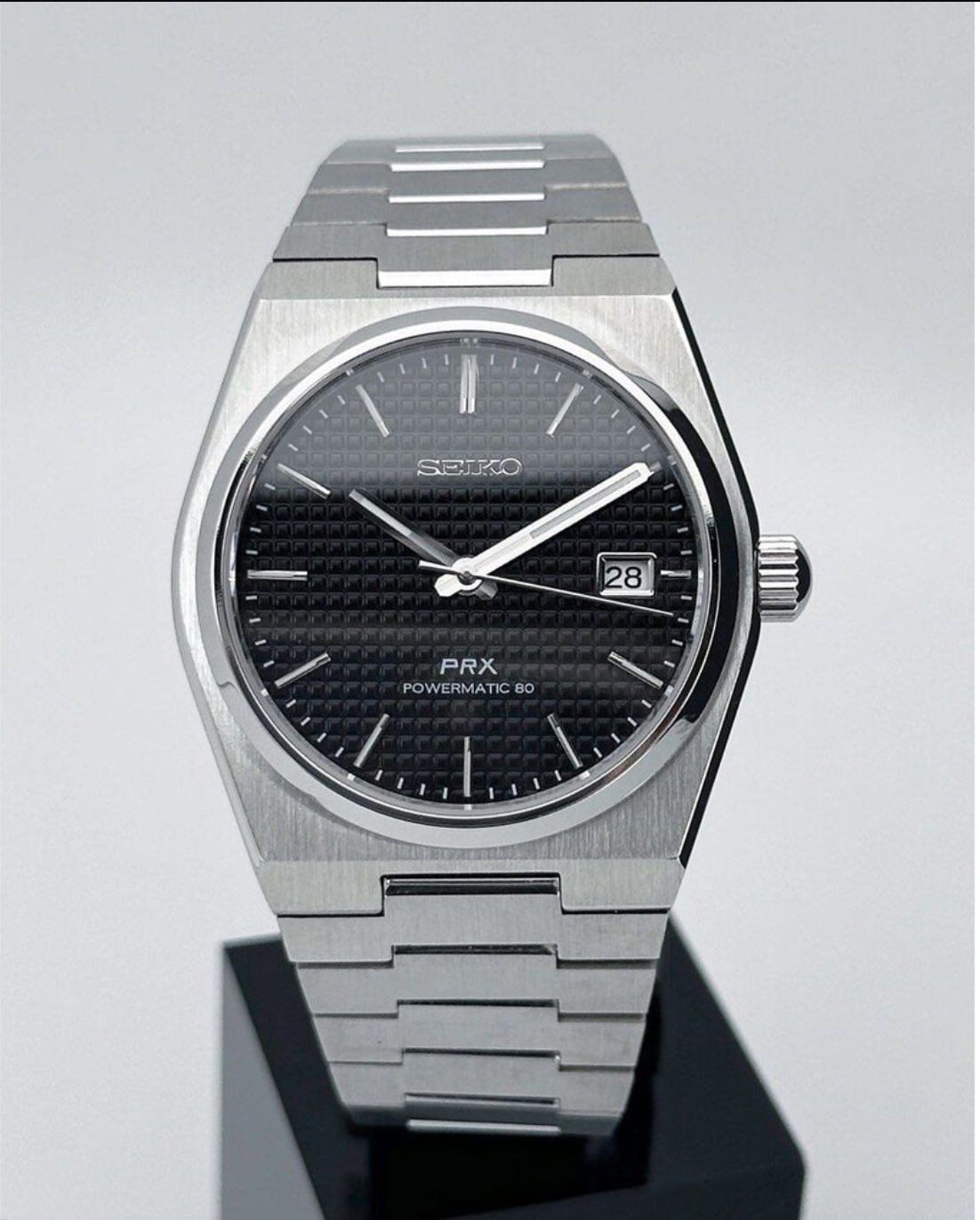 Reloj Seiko Mod PRXeiko de acero inoxidable con dial negro y agujas plateadas.